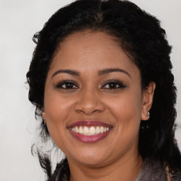 Joyful black young-adult female with long  brown hair and brown eyes