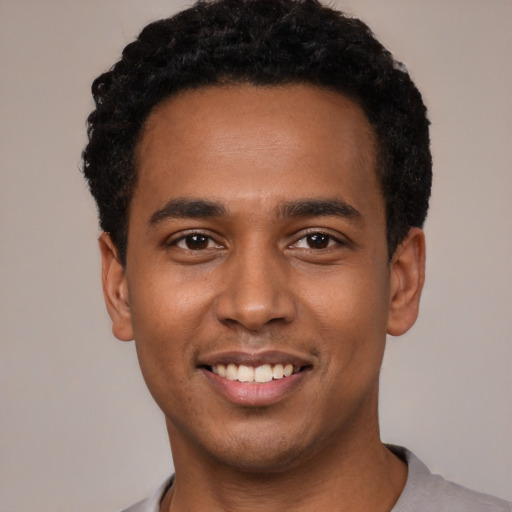 Joyful black young-adult male with short  black hair and brown eyes