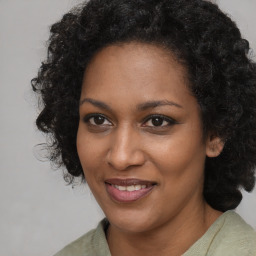 Joyful black adult female with long  brown hair and brown eyes