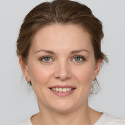 Joyful white young-adult female with medium  brown hair and grey eyes