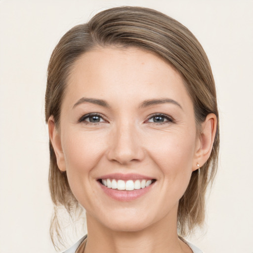 Joyful white young-adult female with medium  brown hair and grey eyes