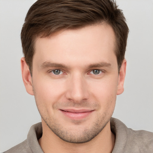 Joyful white young-adult male with short  brown hair and grey eyes