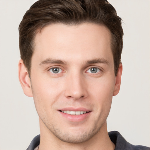 Joyful white young-adult male with short  brown hair and grey eyes