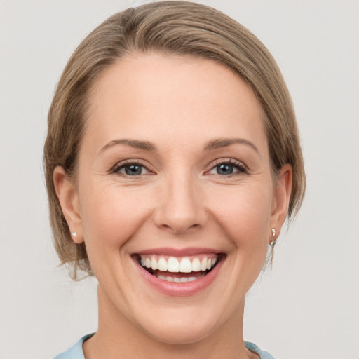 Joyful white young-adult female with medium  brown hair and grey eyes