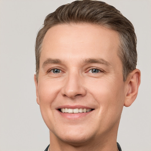 Joyful white young-adult male with short  brown hair and grey eyes