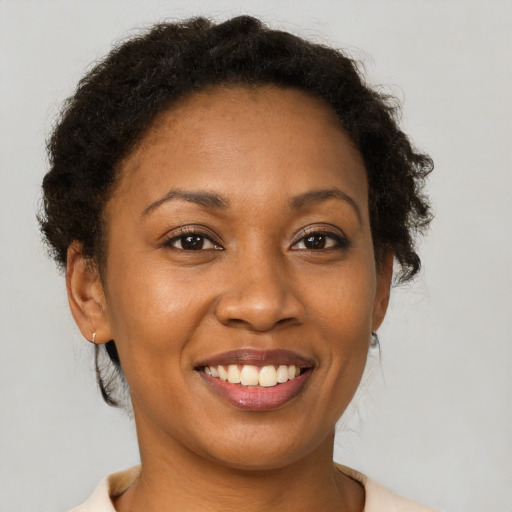 Joyful black young-adult female with short  brown hair and brown eyes