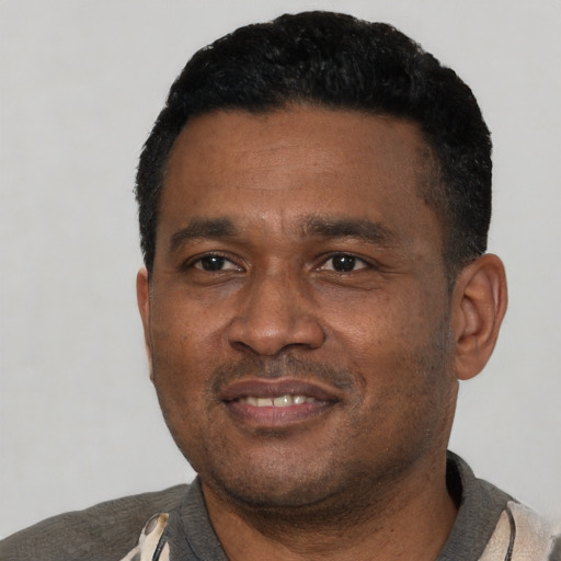 Joyful black adult male with short  black hair and brown eyes