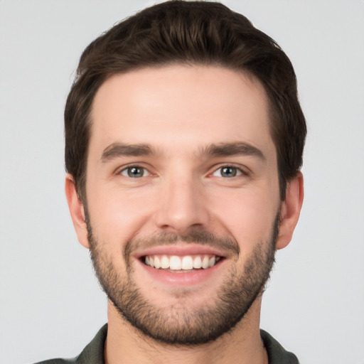 Joyful white young-adult male with short  brown hair and grey eyes