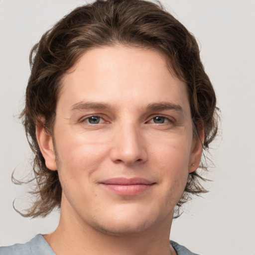 Joyful white young-adult male with medium  brown hair and grey eyes