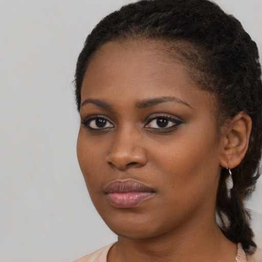 Joyful black young-adult female with long  black hair and brown eyes