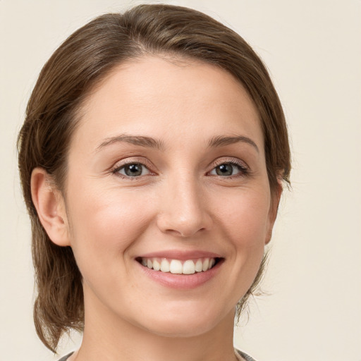 Joyful white young-adult female with medium  brown hair and grey eyes