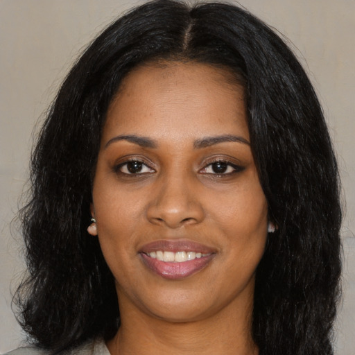 Joyful black young-adult female with long  black hair and brown eyes