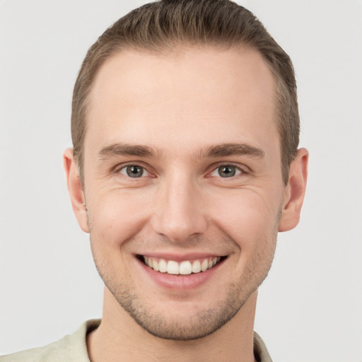 Joyful white young-adult male with short  brown hair and grey eyes