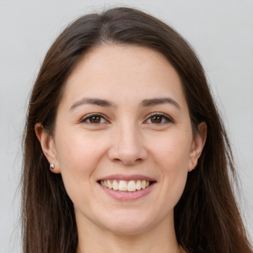 Joyful white young-adult female with long  brown hair and brown eyes