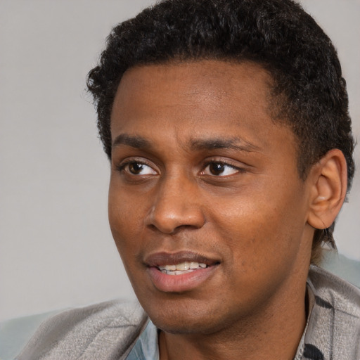 Joyful black young-adult male with short  black hair and brown eyes