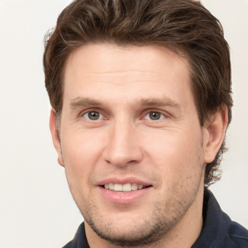 Joyful white young-adult male with short  brown hair and grey eyes