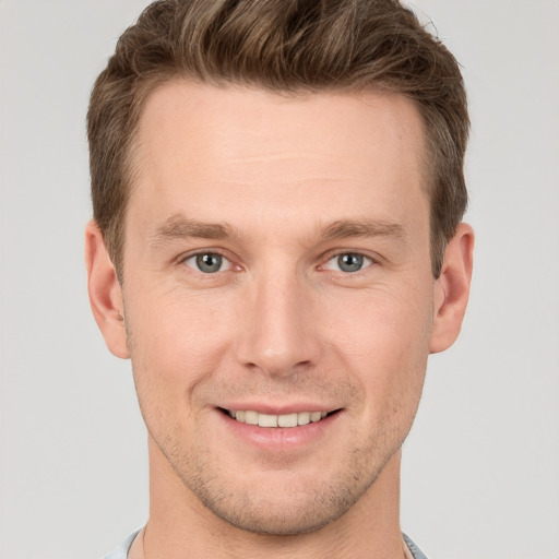 Joyful white young-adult male with short  brown hair and grey eyes