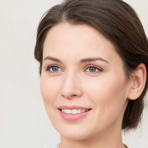 Joyful white young-adult female with medium  brown hair and grey eyes