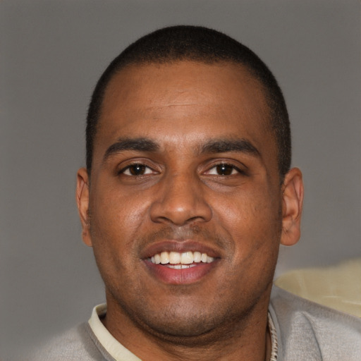 Joyful black young-adult male with short  brown hair and brown eyes