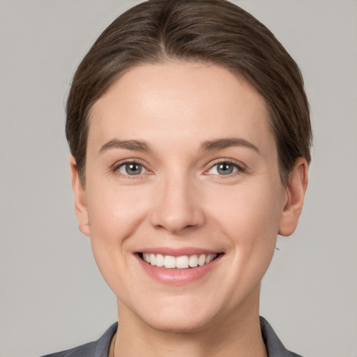 Joyful white young-adult female with short  brown hair and grey eyes