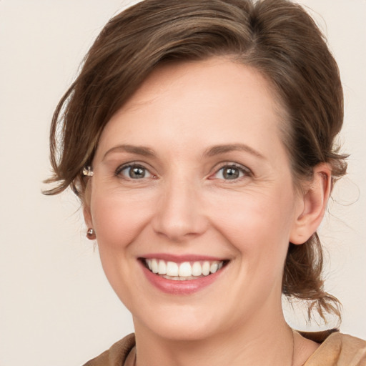 Joyful white young-adult female with medium  brown hair and grey eyes