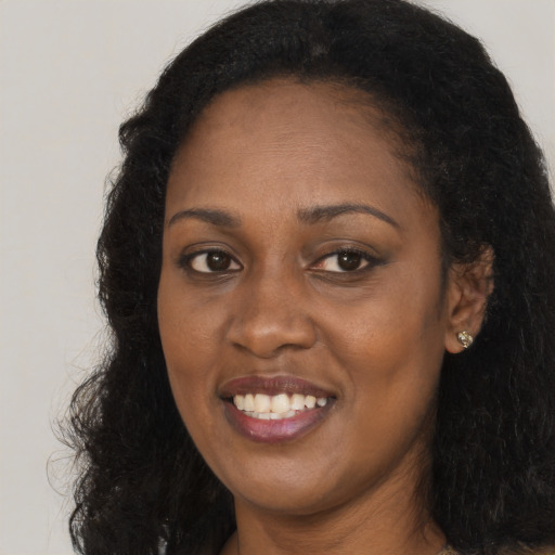Joyful black young-adult female with long  brown hair and brown eyes