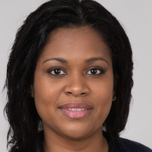 Joyful black young-adult female with long  brown hair and brown eyes