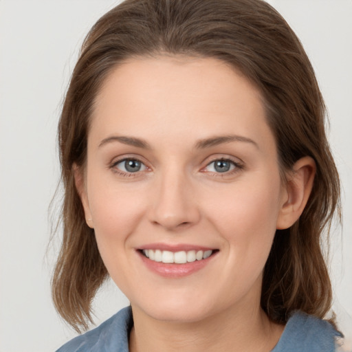 Joyful white young-adult female with medium  brown hair and grey eyes