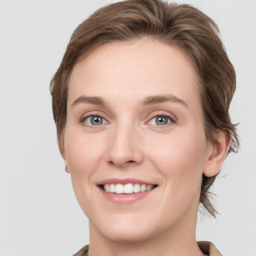 Joyful white young-adult female with medium  brown hair and grey eyes