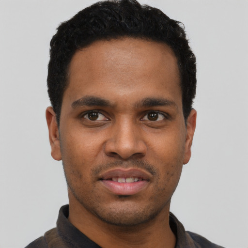 Joyful black young-adult male with short  black hair and brown eyes