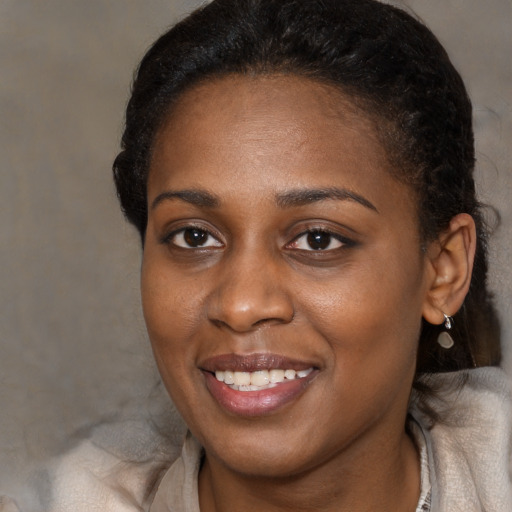 Joyful black young-adult female with long  brown hair and brown eyes