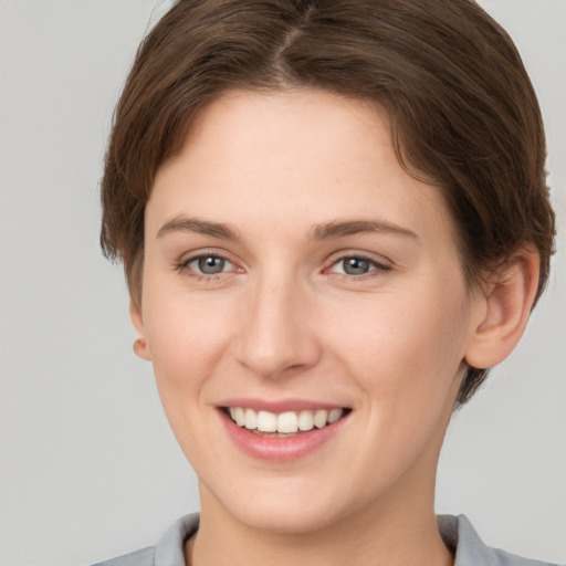 Joyful white young-adult female with short  brown hair and grey eyes