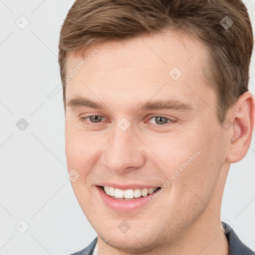 Joyful white young-adult male with short  brown hair and grey eyes