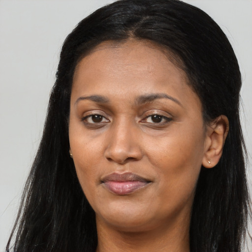 Joyful black young-adult female with long  brown hair and brown eyes