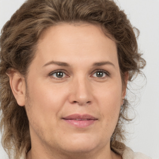 Joyful white adult female with medium  brown hair and green eyes