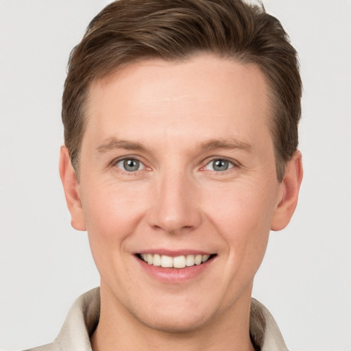 Joyful white young-adult male with short  brown hair and grey eyes