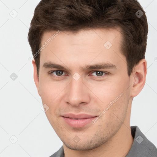 Joyful white young-adult male with short  brown hair and grey eyes