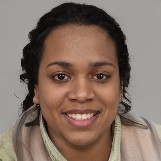 Joyful black young-adult female with long  brown hair and brown eyes