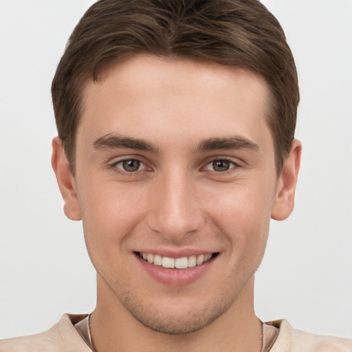 Joyful white young-adult male with short  brown hair and grey eyes