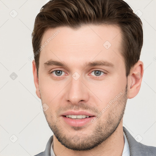 Joyful white young-adult male with short  brown hair and grey eyes