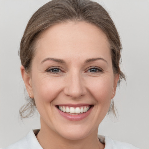 Joyful white young-adult female with medium  brown hair and grey eyes