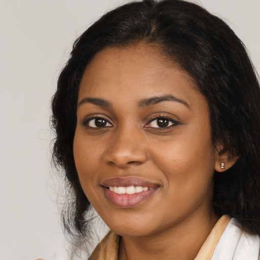 Joyful black young-adult female with long  brown hair and brown eyes