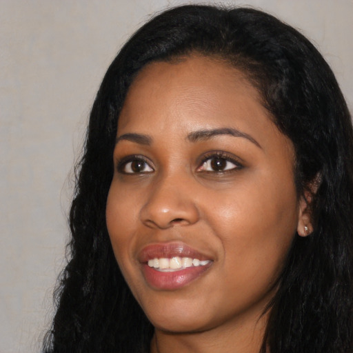 Joyful black young-adult female with long  black hair and brown eyes