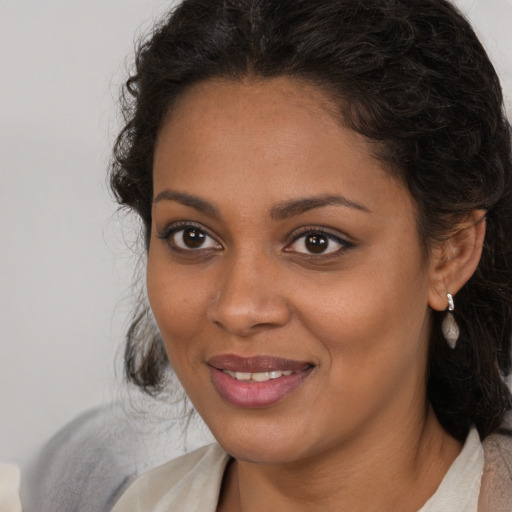 Joyful black young-adult female with long  brown hair and brown eyes