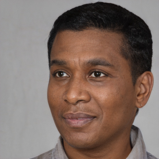 Joyful black adult male with short  black hair and brown eyes
