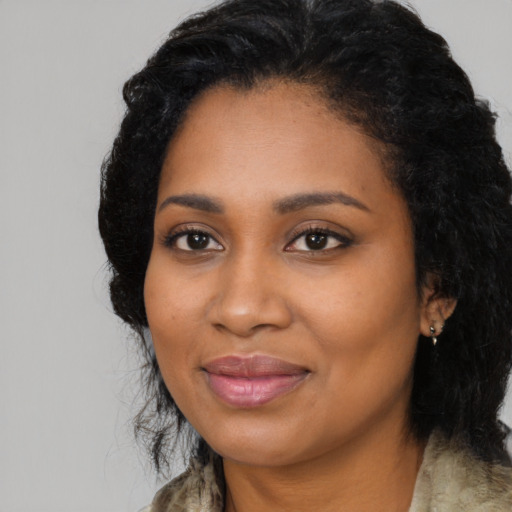 Joyful black young-adult female with long  black hair and brown eyes