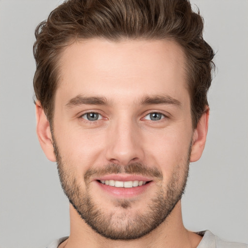 Joyful white young-adult male with short  brown hair and grey eyes