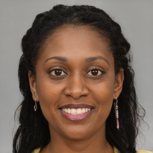 Joyful black young-adult female with long  brown hair and brown eyes