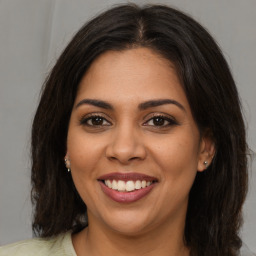 Joyful latino young-adult female with medium  brown hair and brown eyes