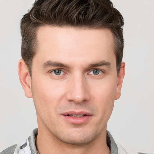 Joyful white young-adult male with short  brown hair and grey eyes